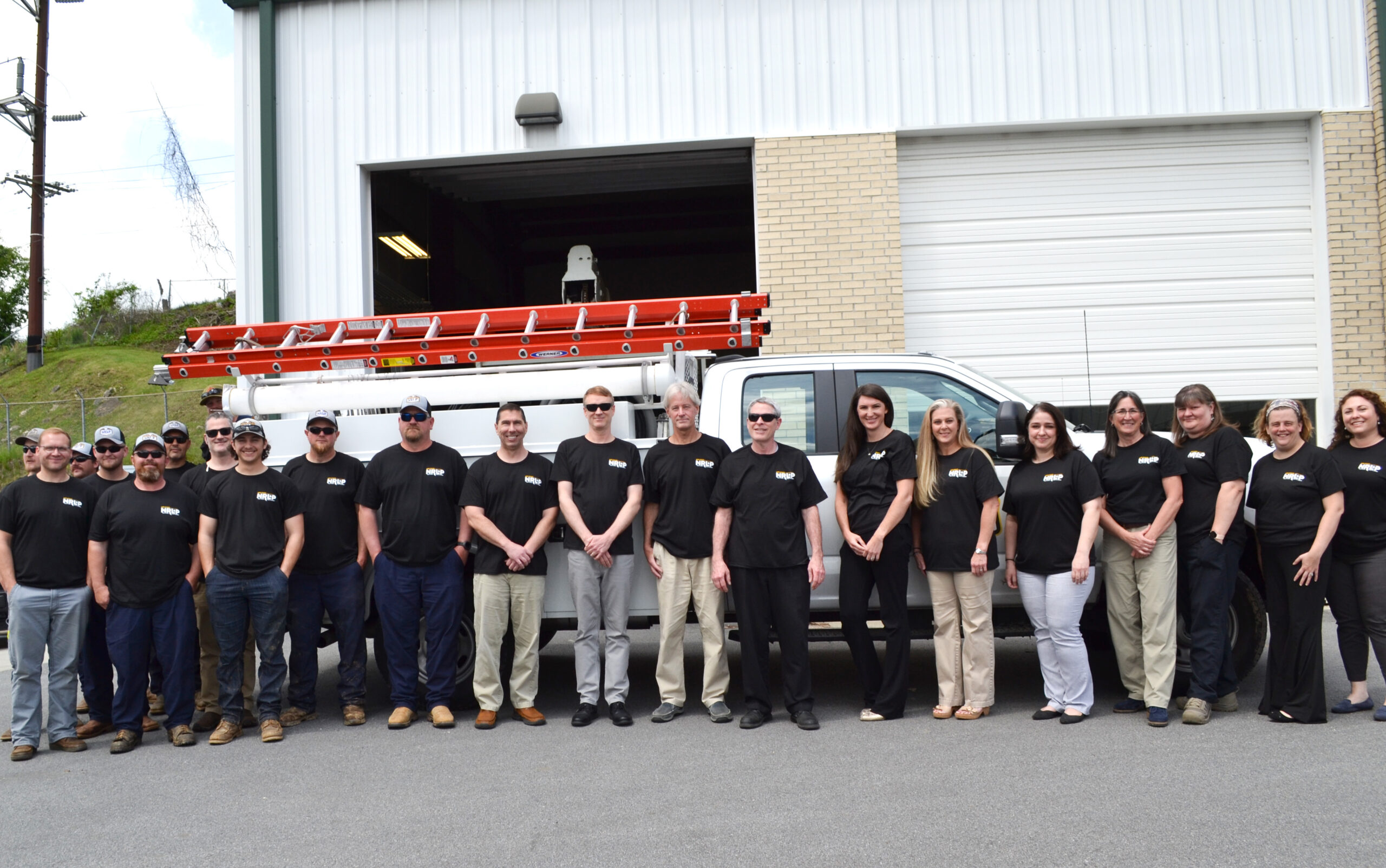 The NRLP team stands in front of a truck wearing Month of Giving shirts
