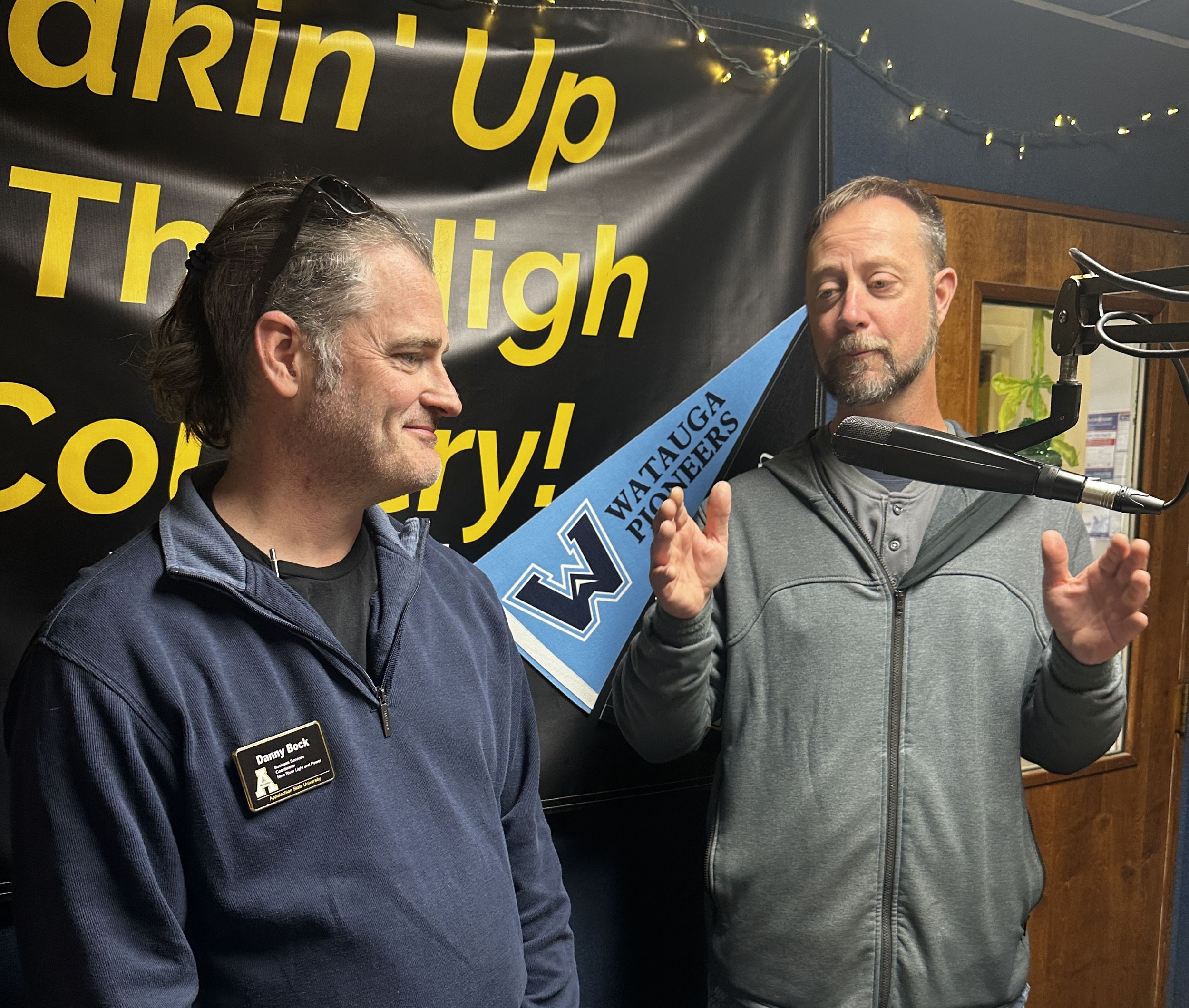 Two NRLP team members speak into a microphone during a radio interview.