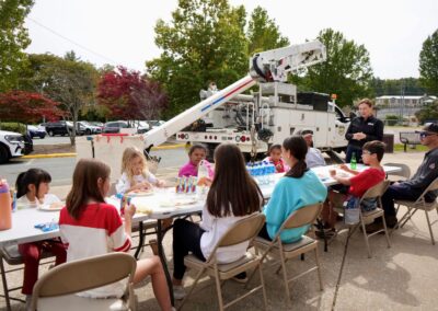 A group of students having lunch outside with NRLP team members in front of a bucket truck